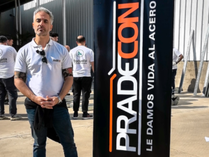 Arq. Julio González, representante de PRADECON, junto al banner de la empresa en el taller