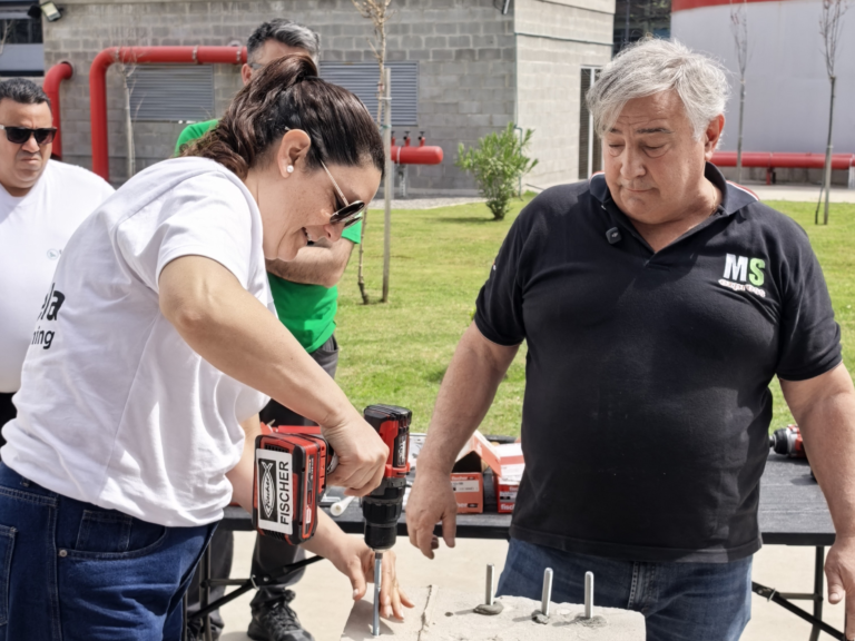 Participante perfora un bloque de hormigón para colocar un anclaje, con la guía de un especialista